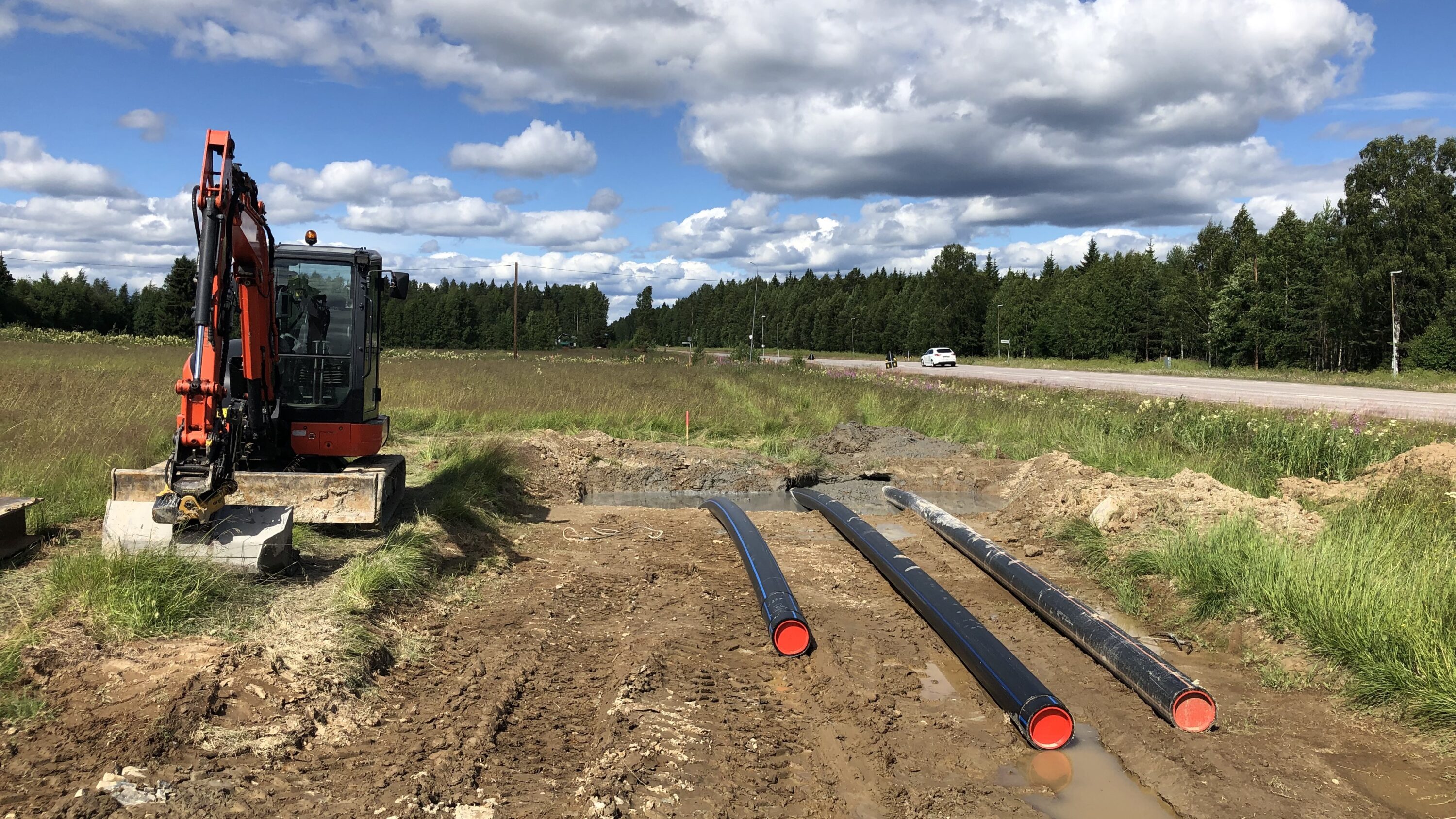 Bild på rörledningar vid en stor väg och arbetsmaskiner vid sidan av