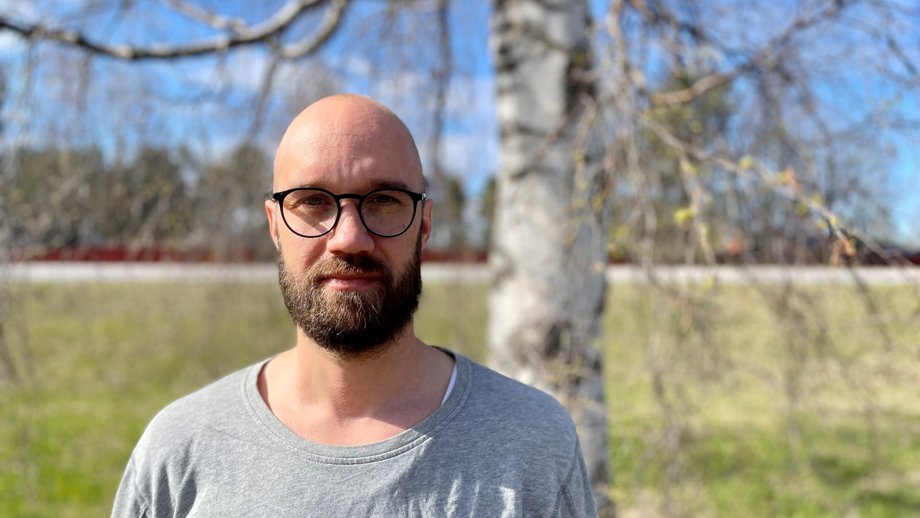 Människa utomhus vid träd i solig vårdag