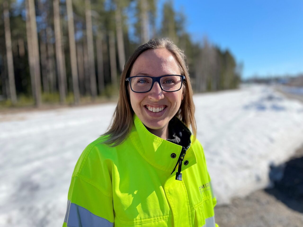 Människa i skydds- och arbetskläder utomhus i sol och snö