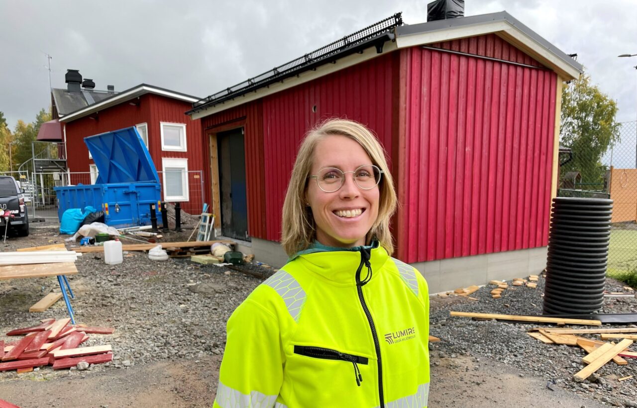 Människa i arbetskläder vid rött mindre hus