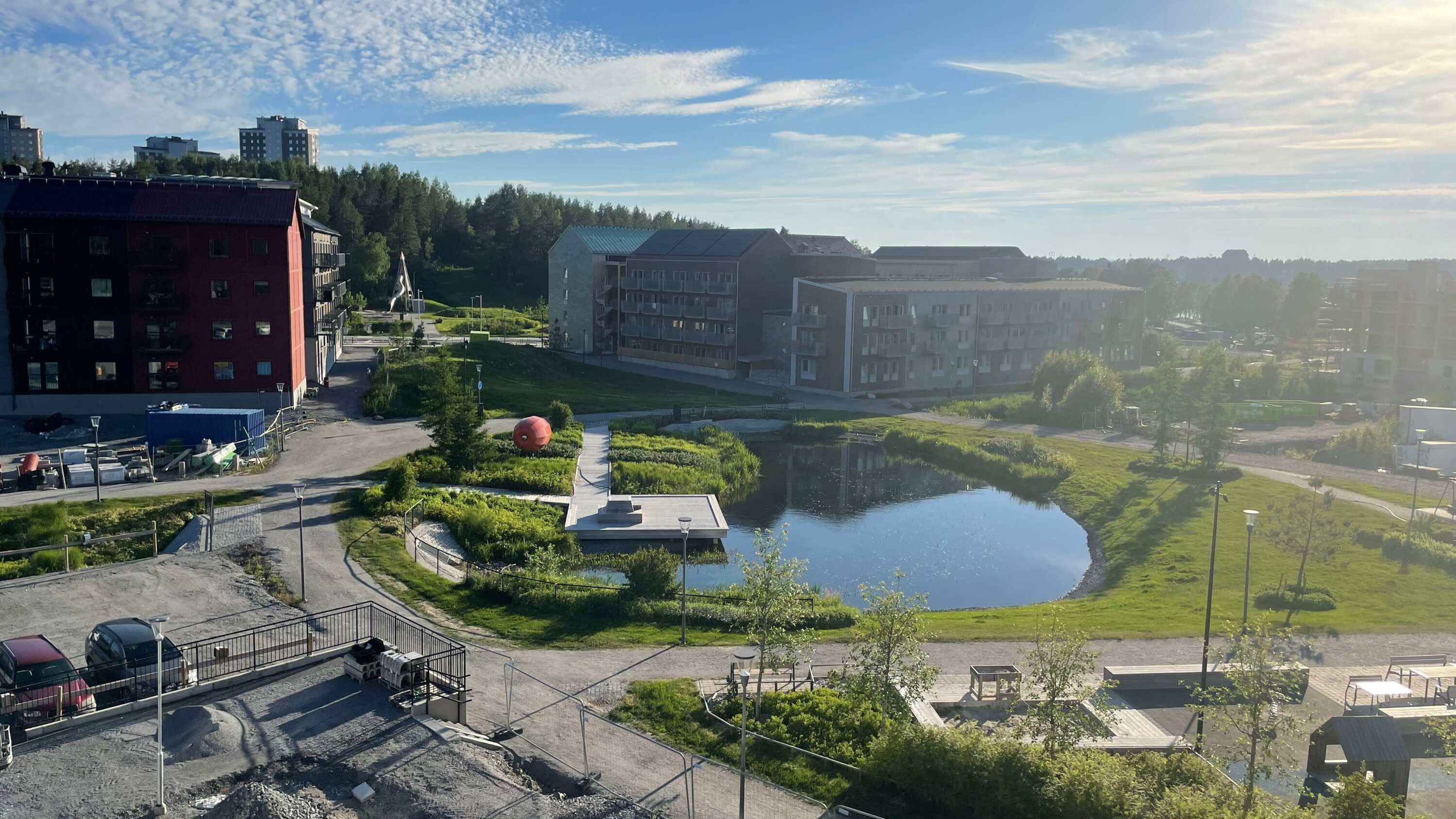 En damm omgiven av höga hus en sommarkväll i sol
