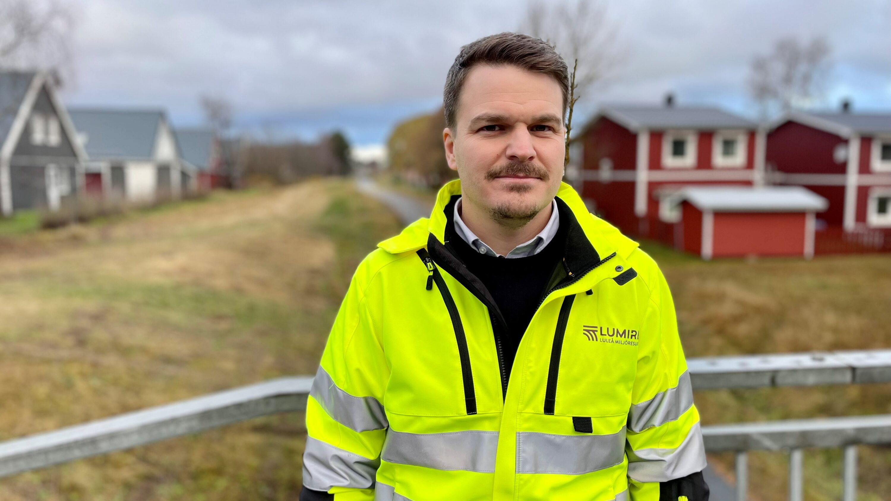 Människa i gula varselkläder utomhus vid bostadsområde