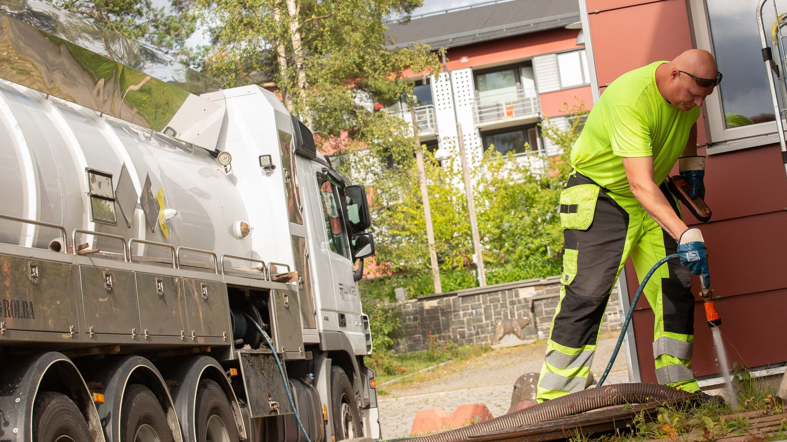 Man i varselkläder spolar vatten genom slang