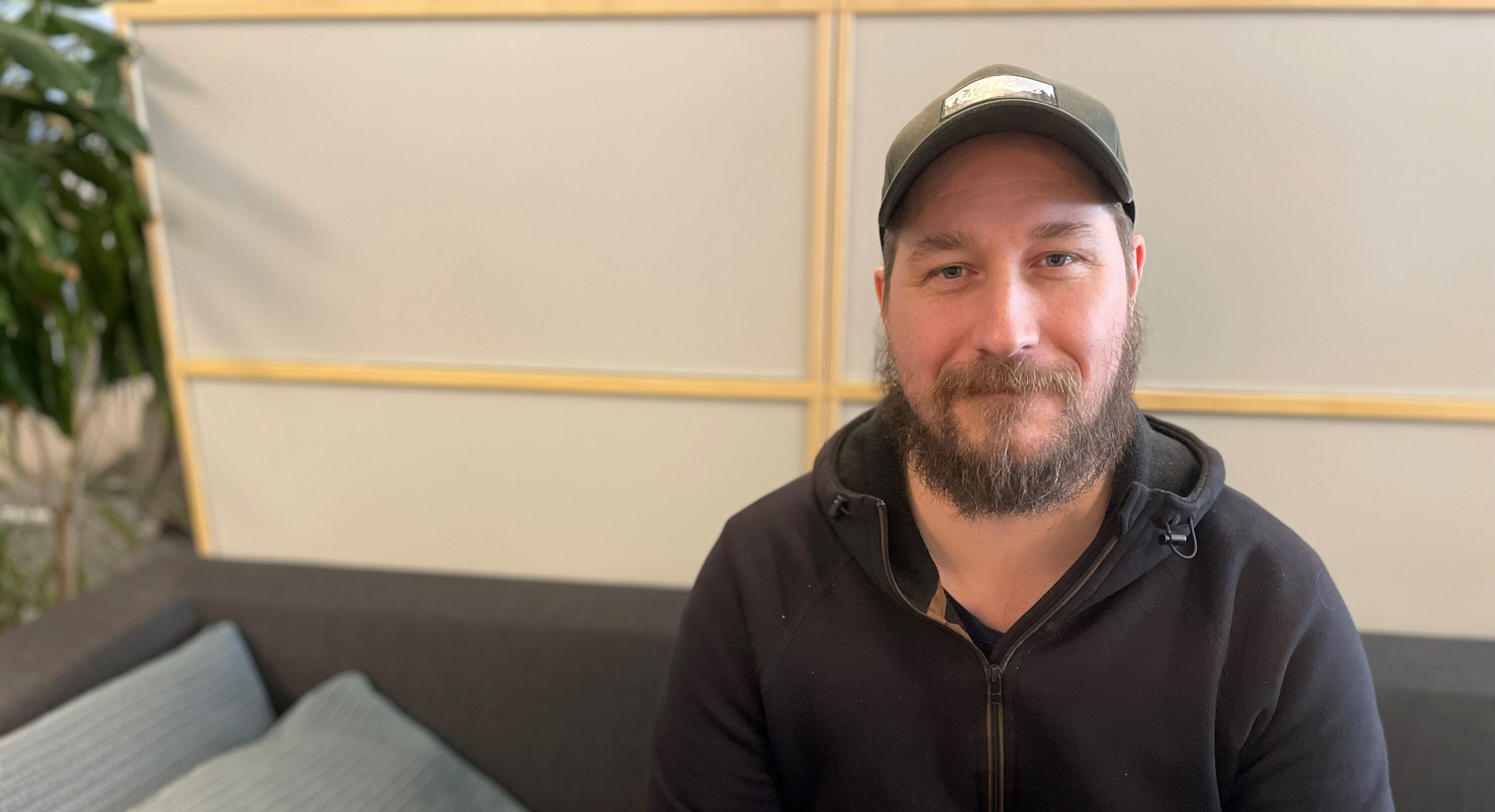 Bild på människa i keps som sitter i soffa