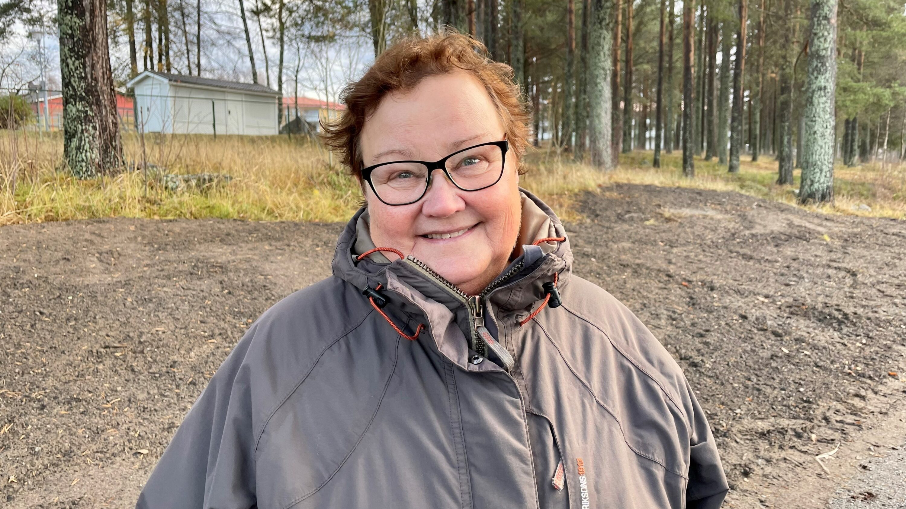 bild på leende människa utomhus vid skog höst