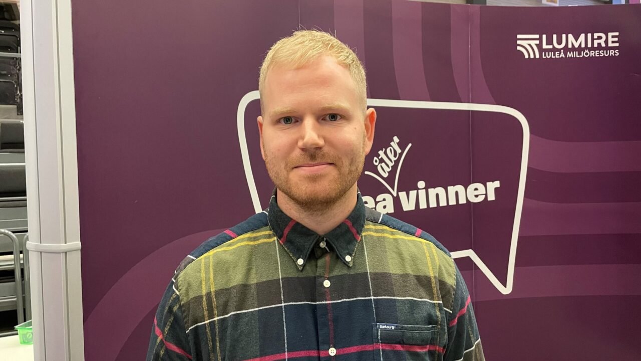 Bild på människa framför skärmvägg på mässa