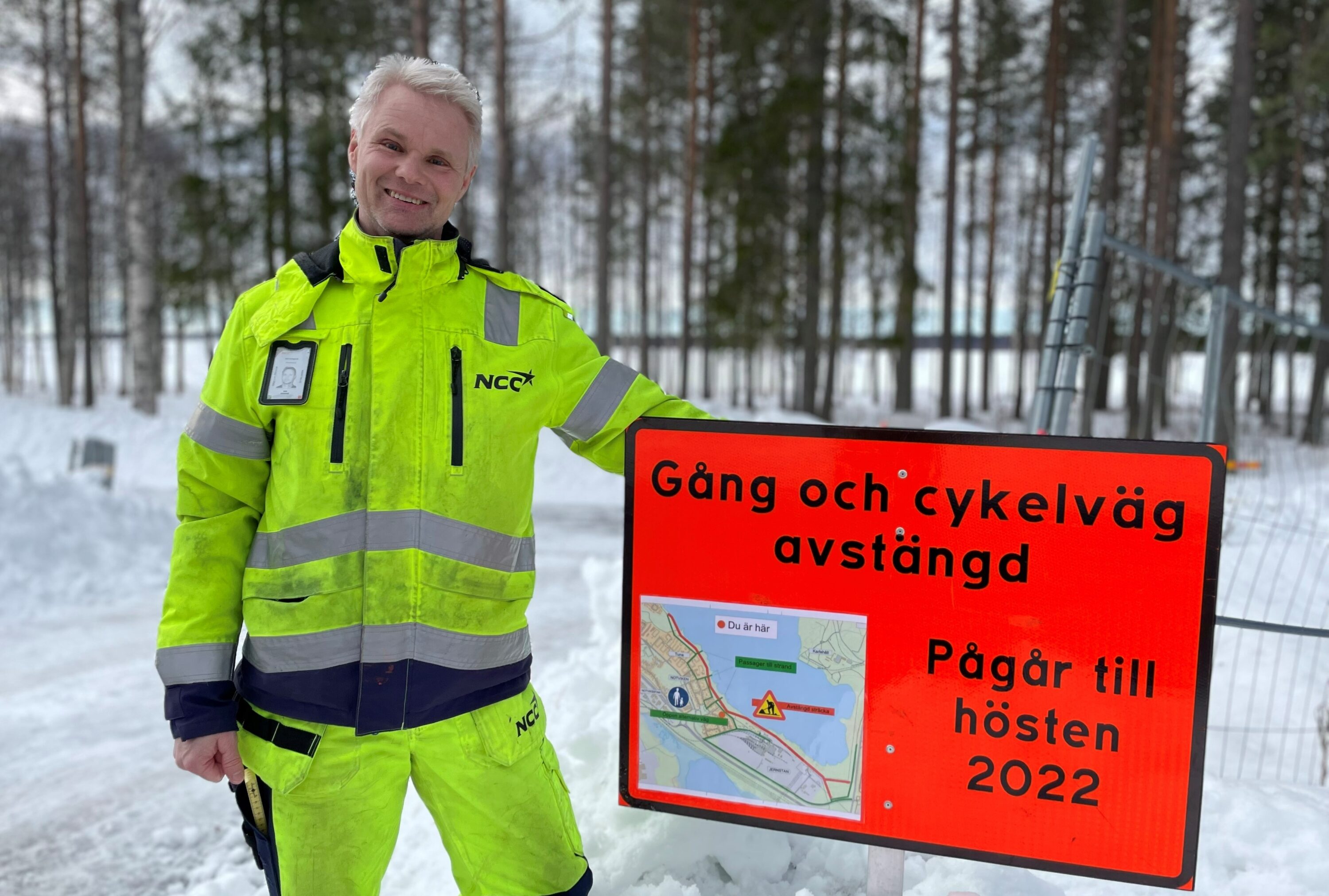 Människa i gula skyddskläder vid skylt vid passage
