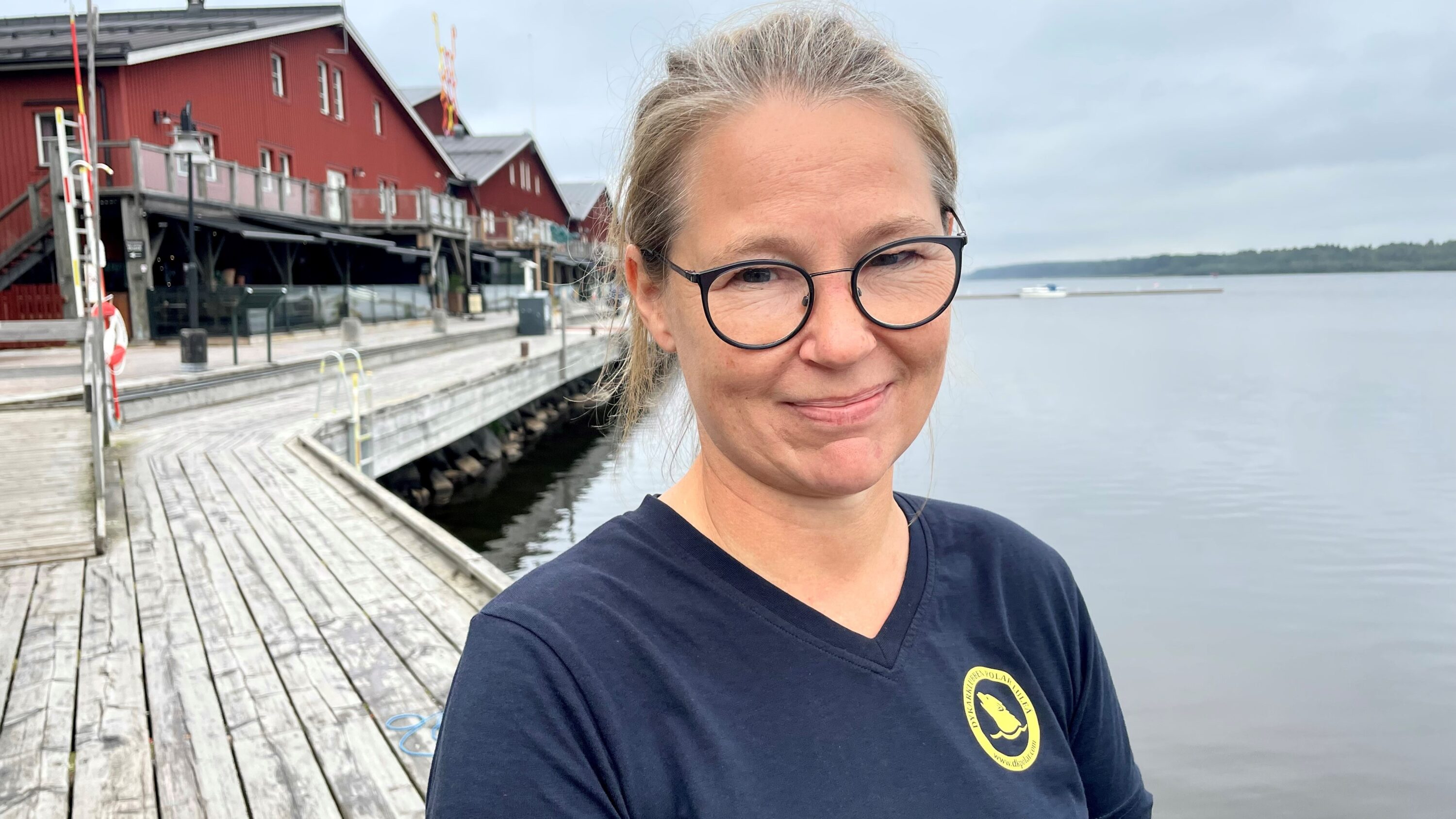 Människa utomhus vid kaj med vatten i bakgrunden sommar