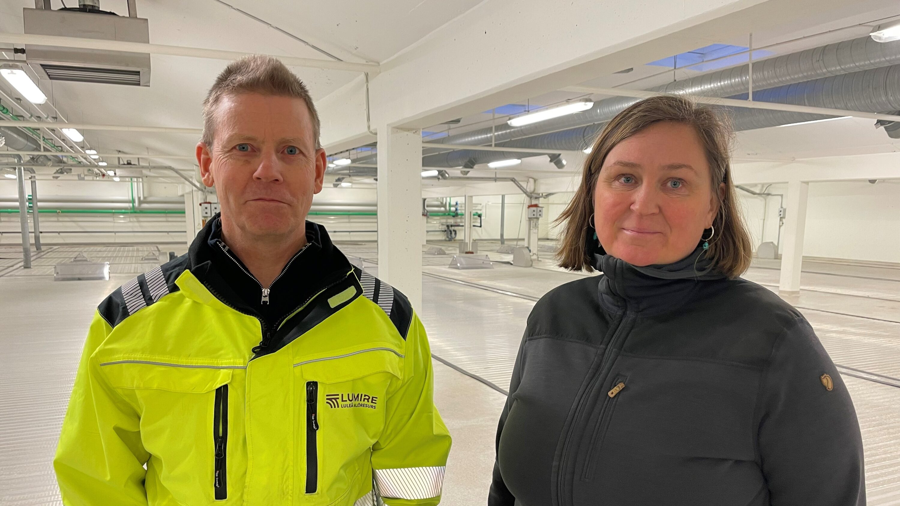 Bild på två människor varav en i gula varsel o arbetskläder inomhus i ett avloppsreningsverk